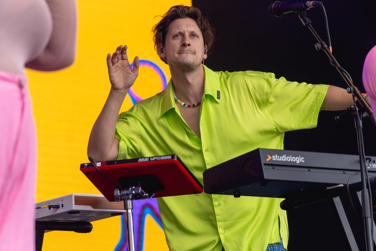 Barry Can't Swim performing at Glastonbury 2024, arms raised over keyboards and pads in a lime shirt