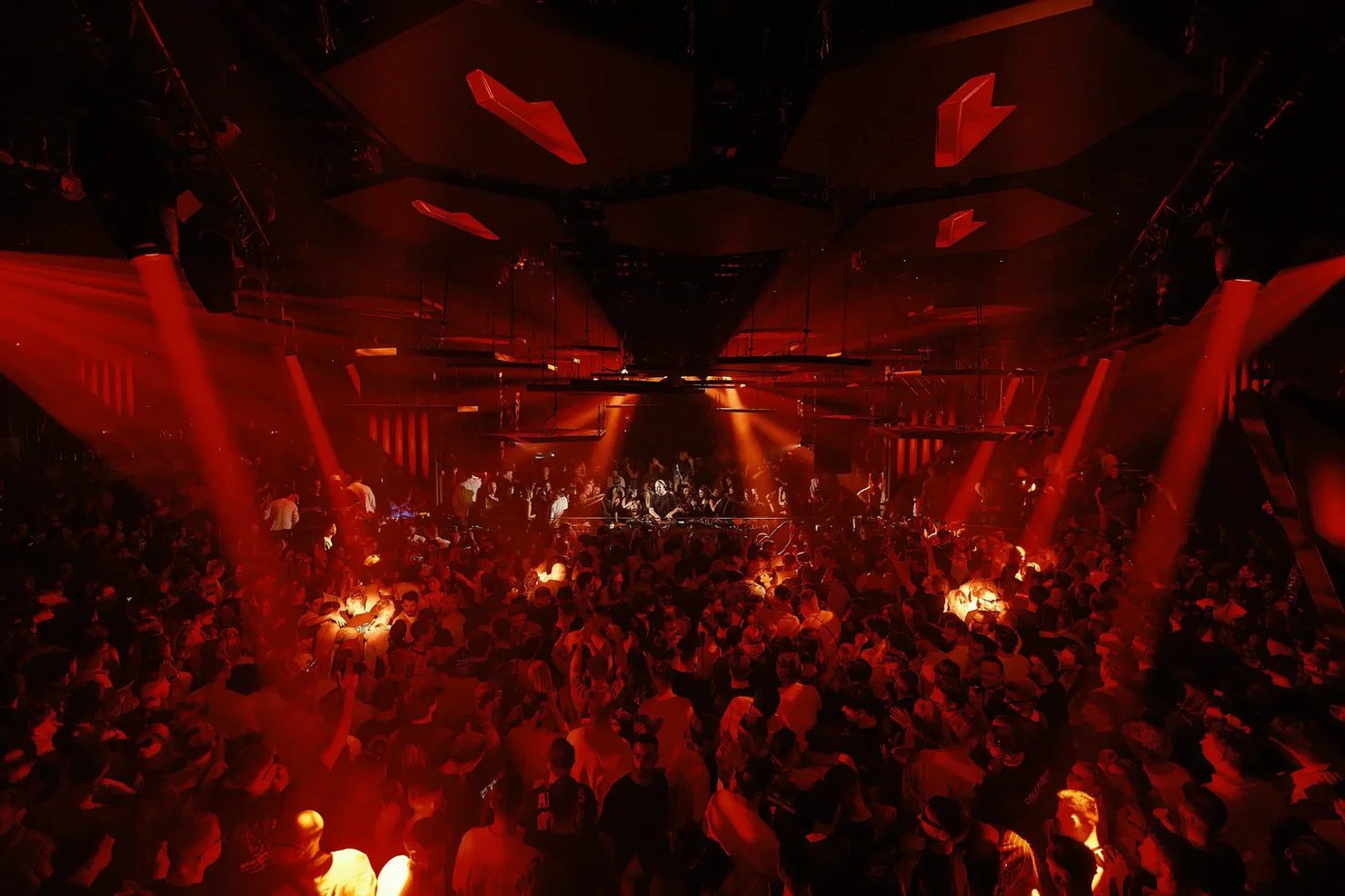 Packed crowd in deep red light at an Ibiza tech-house club