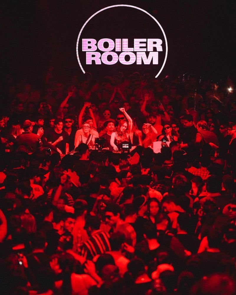 Hands in the air at a Boiler Room set, the camera-facing crowd the brand built its myth on