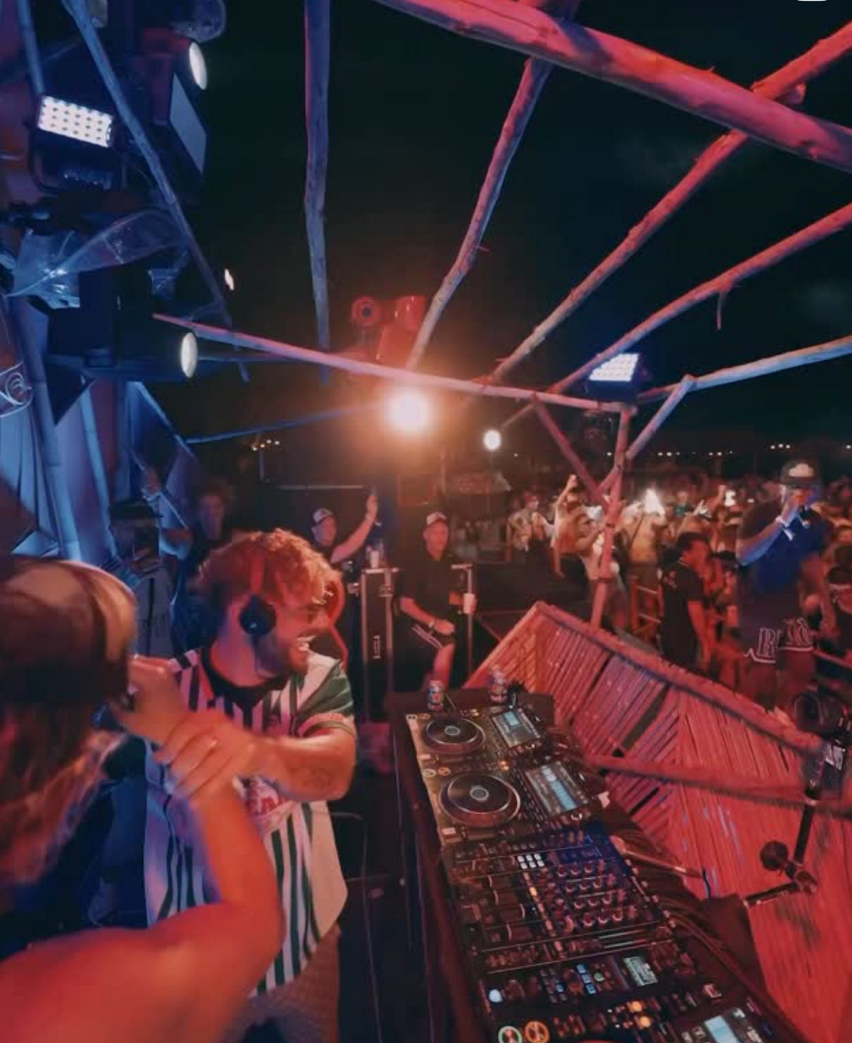 DnB Allstars DJ booth with crowd and red stage lighting during outdoor drum and bass event