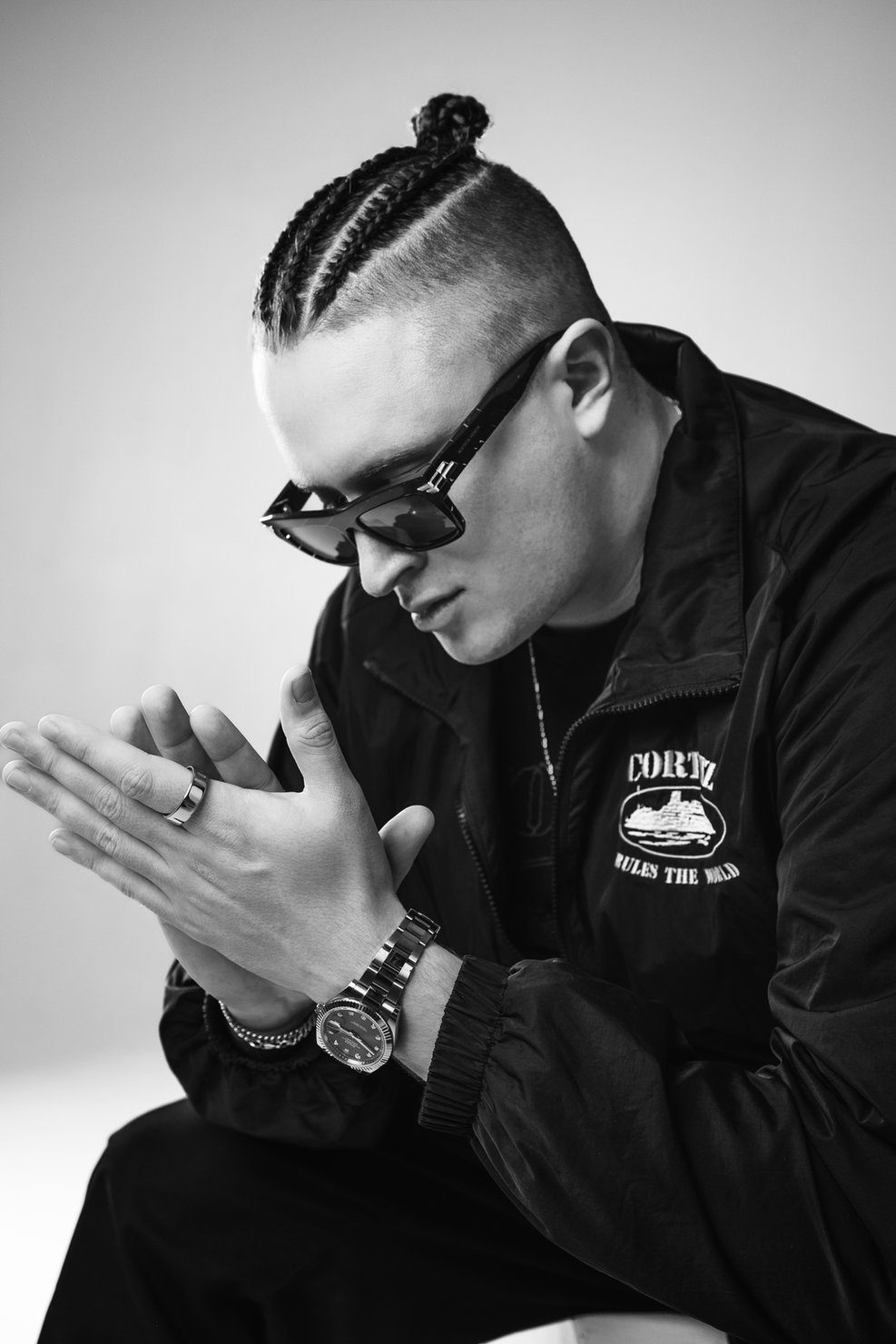 MNEEMO (Yaroslav Gorovoy) wearing glasses and braids, with his arms folded, in a black jacket with the text “Cortez Rules the World.” Black-and-white photo, calm expression.