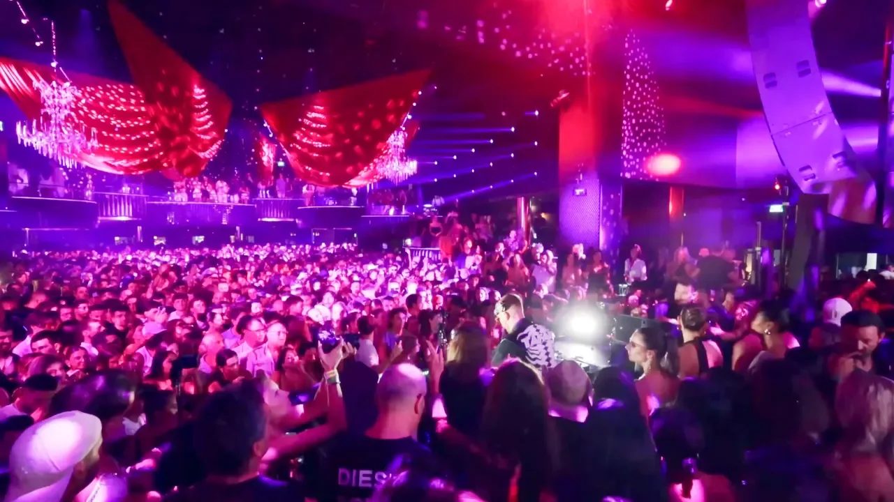 Packed crowd under pink lights and lasers inside Hi Ibiza