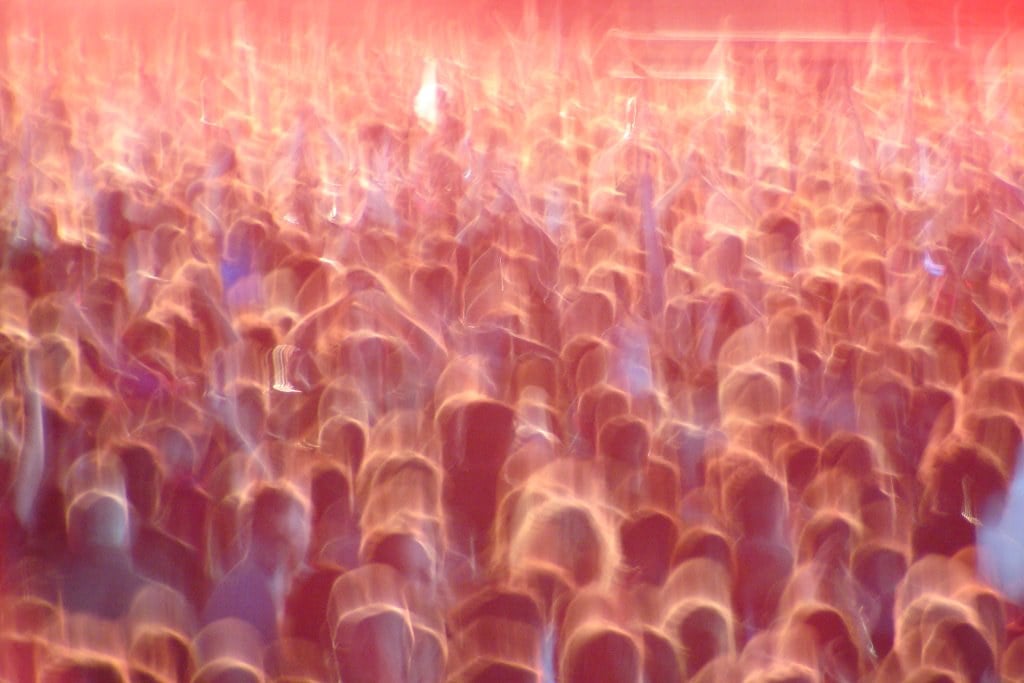 A festival crowd blurred in red light, hands in the air, the audience Wireless has to win back for a 2027 return