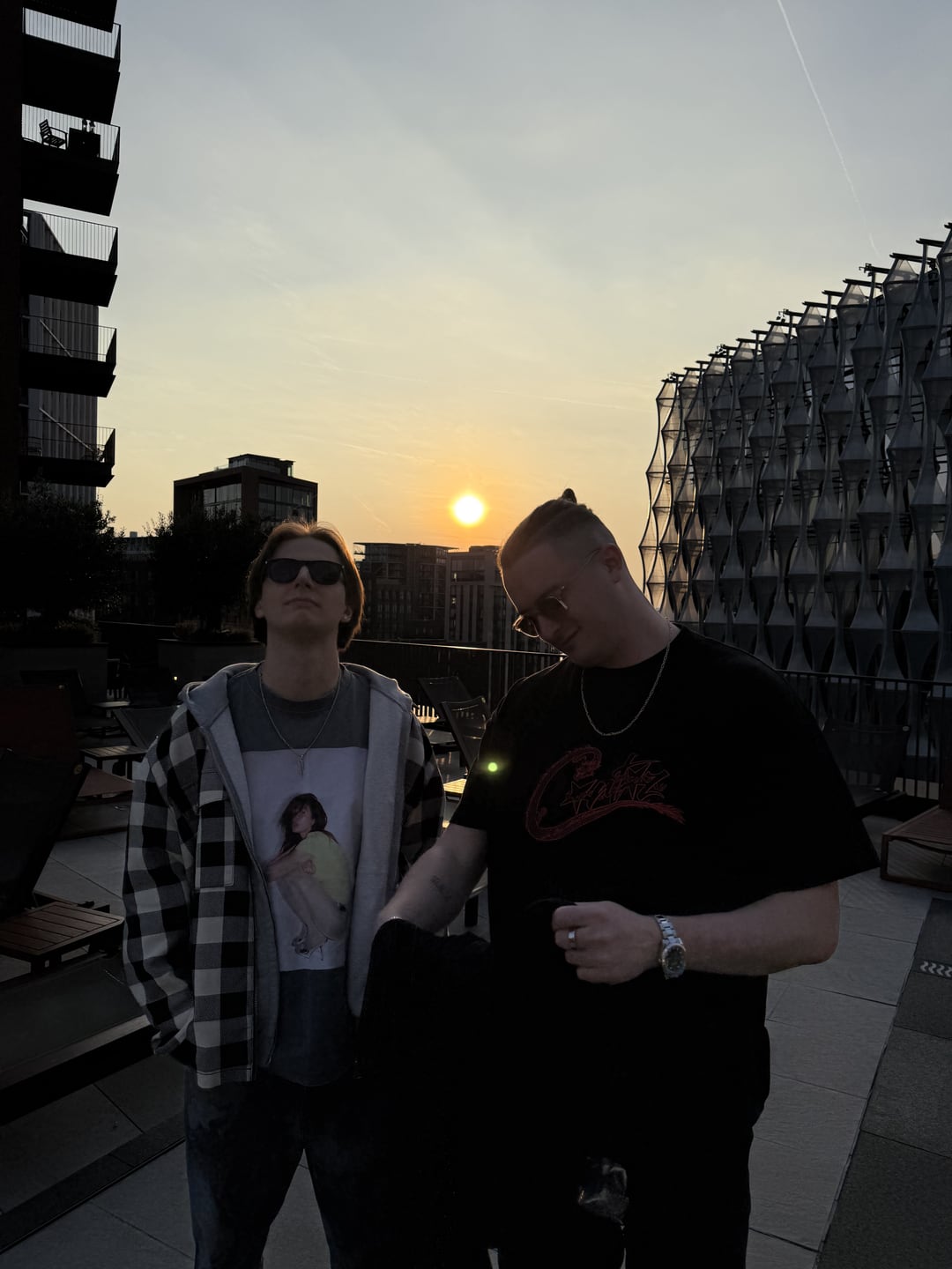 MNEEMO and FLASH on a rooftop at sunset, the sun dropping behind London buildings.