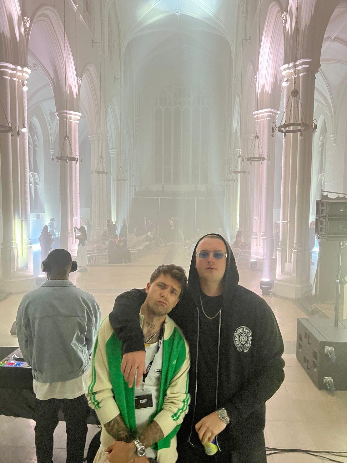 MNEEMO (Yaroslav Gorovoy) & E4TEEN posing inside a Gothic church interior. One is wearing a green jacket, the other is dressed in black with a hoodie. Smoky atmosphere, informal style.
