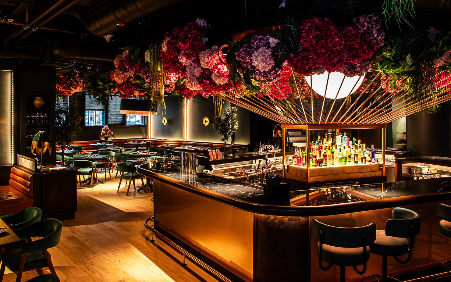 45 London on 45 Curtain Road. Elegant bar interior with vibrant floral ceiling, dim lighting, and modern chairs. Bottles displayed on the counter, evoking a cozy ambiance.
