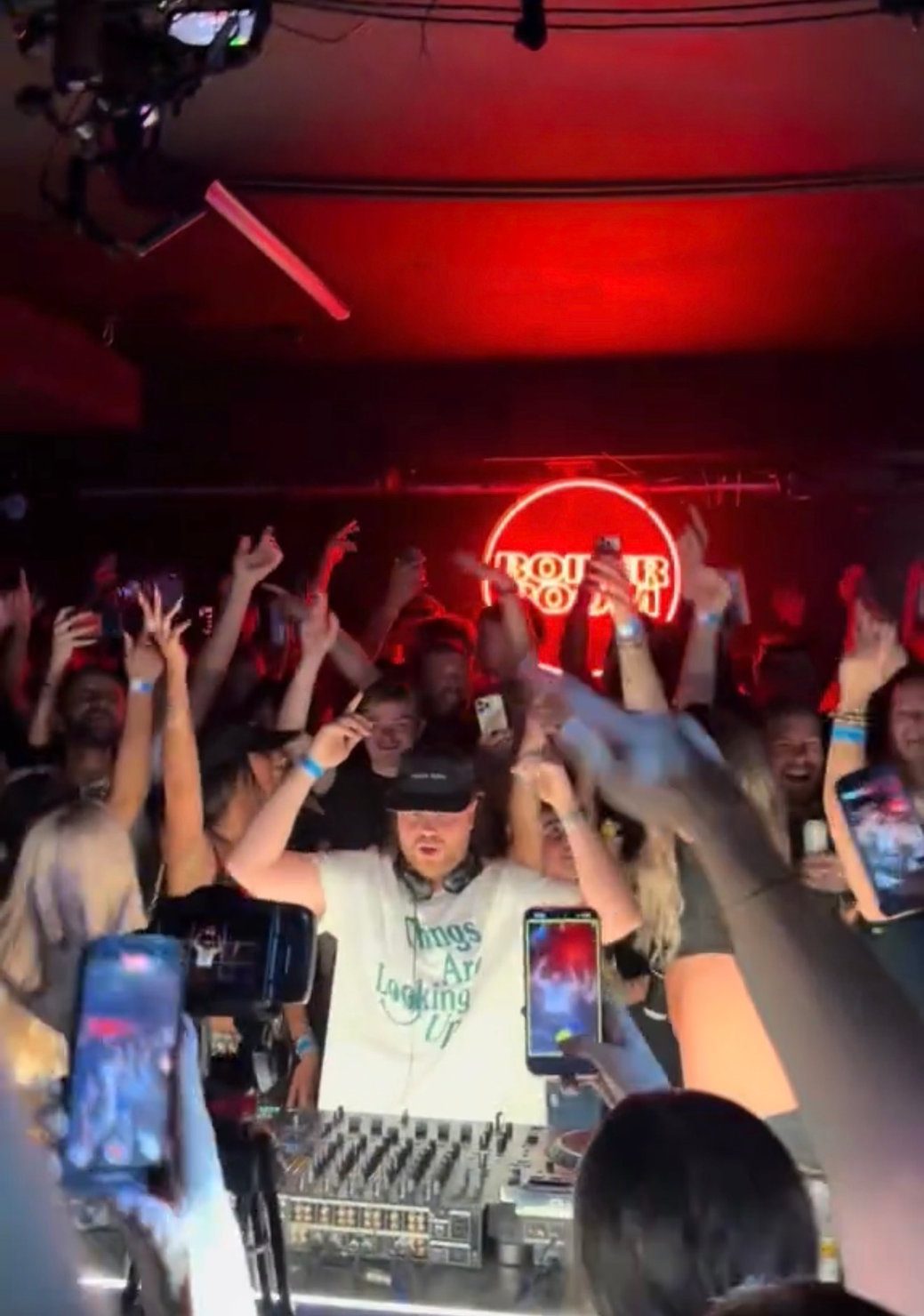 Crowd raising their hands as Rossi. plays his Boiler Room London debut set on 13 May 2026, with red club lighting and the Boiler Room logo behind the DJ booth.