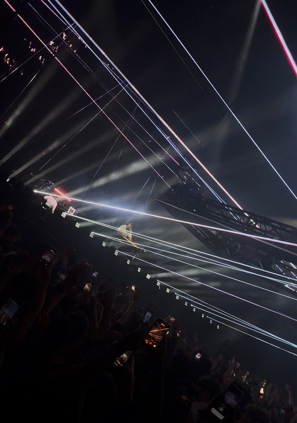 Sammy Virji DJing at Alexandra Palace on stage amid bright, colorful laser lights and a cheering crowd, creating an energetic concert atmosphere. 18 April 2026.