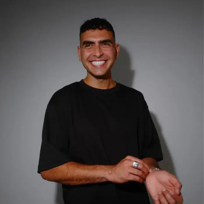 Sammy Virji portrait smiling in a black T-shirt, used in MNEEMO’s editorial article on his 2026 Finsbury Park headline show.