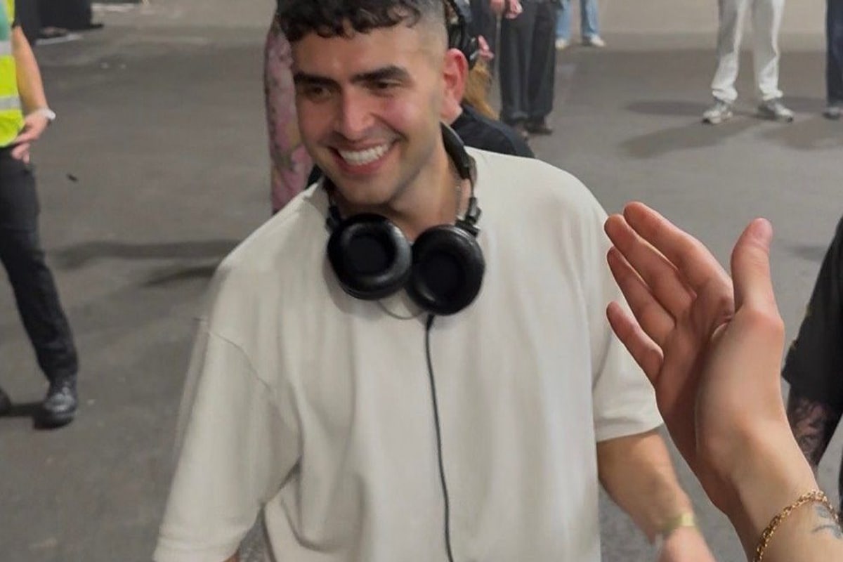 Sammy Virji backstage at Alexandra Palace after his show, headphones round his neck, greeting a fan