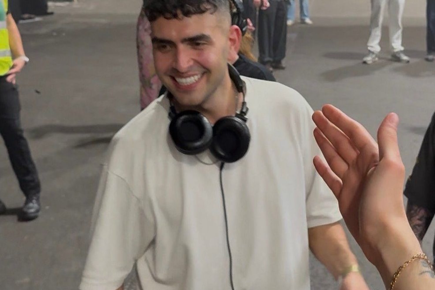 Sammy Virji backstage at Alexandra Palace after his show, headphones round his neck, greeting a fan