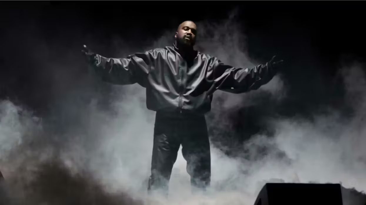 Kanye West (Ye) standing during his performance in Los Angeles, wearing a black leather jacket against a black background, with heavy smoke surrounding him.