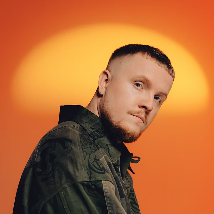 Chris Stussy photographed against a glowing orange sunburst backdrop, the Dutch DJ and producer behind Up The Stuss and his USS night at Pacha Ibiza